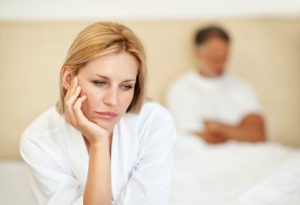 Portrait of thoughtful beautiful woman with man in background at home